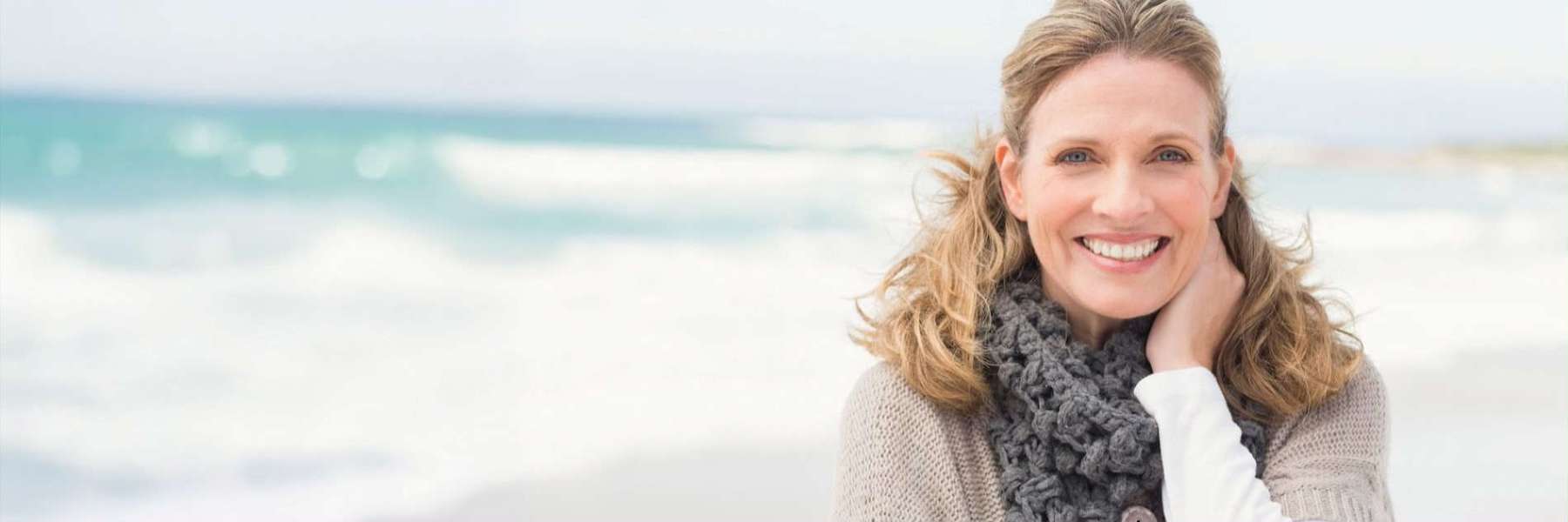 woman smiling while sitting on the beach